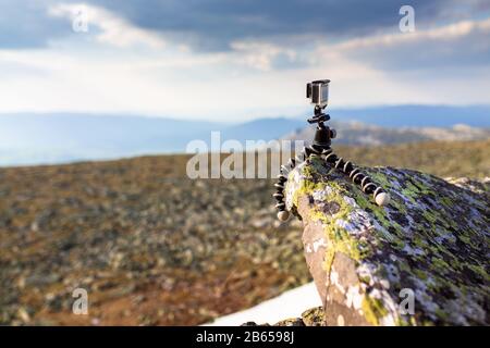 compact action camera mounted on a flexible tripod gorilla on rock in mountains Stock Photo