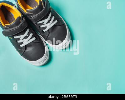 pair of new kids or adult sneakers on blue background, top view. Flat lay gray and yellow or mustard color sneakers shoes on colorful bright blue background with copy space for text or design Stock Photo