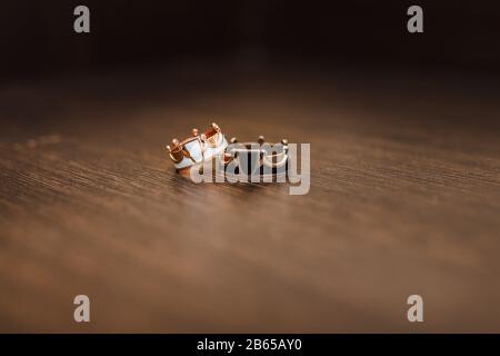 Golden wedding rings with crown shape on wooden background. Shallow focus Stock Photo
