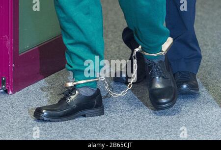 10 March 2020, Schleswig-Holstein, Lübeck: An accused prisoner goes into the courtroom of the regional court and wears shackles on his feet. The man is said to have taken a psychologist hostage in the Lübeck prison in June 2019 and threatened her with a knife in order to force his deportation to Romania. (to dpa 'Trial against suspected hostage-takers from Lübeck prison begins') Photo: Daniel Bockwoldt/dpa Stock Photo