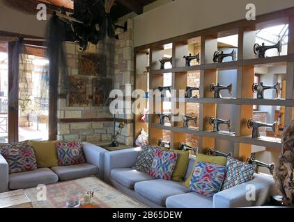 Partial view of living room decorated with collection of vintage sewing machines on a bookshelf and colourful sofas with cushions. Stock Photo