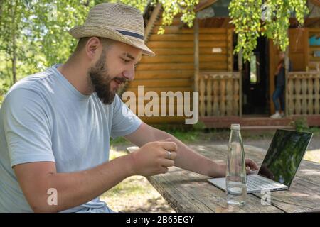 Bearded man freelancer work on laptop. Young business man using laptop for work online outdoor. Stock Photo