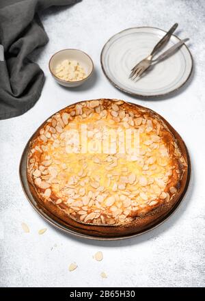 Traditional Cheese cake sprinkled with almonds flakes on a light rustic background. Delicious homemade sweet food concept. Selective focus. Stock Photo
