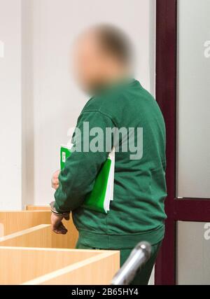 10 March 2020, Schleswig-Holstein, Lübeck: An accused prisoner enters the hall in the regional court. The man is said to have taken a psychologist hostage and threatened her with a knife in June 2019 in the Lübeck prison in order to force his deportation to Romania. (to dpa 'Trial against suspected hostage-takers from Lübeck prison begins') Photo: Daniel Bockwoldt/dpa - ATTENTION: The defendant was pixelated for legal reasons Stock Photo