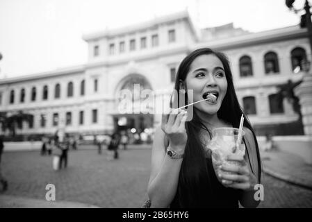 Happy young beautiful Asian tourist woman eating street food Stock Photo