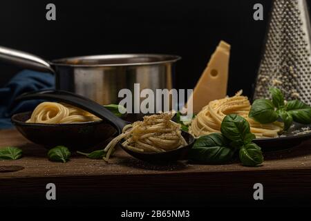 Delicious pasta composition tomato sauce home made basil cheese and tasty with black background. hand holding spoon and serving sauce, salt spices Stock Photo