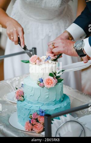 Beautiful turquoise festive cake cutting by the newlyweds at the wedding ceremony Stock Photo
