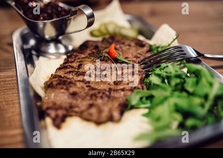 Healthy lean grilled medium rare beef steak and vegetables and a leafy green herb salad in a rustic pub or tavern Stock Photo