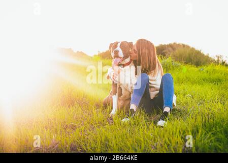 Beatiful young woman kissing dog in the field. American Staffordshire terrier Stock Photo