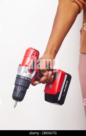 The hand of a woman of African ethnicity holding a cordless screwdriver in her hand Stock Photo