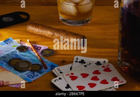 Gambling -  Tobacco Cigar , playing cards, Scotch whiskey and mexico banknotes on the  wooden table Stock Photo