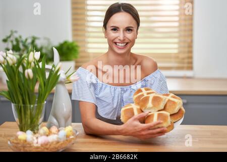 Happy adult woman preparing hot cross buns for Easter in the kitchen Stock Photo