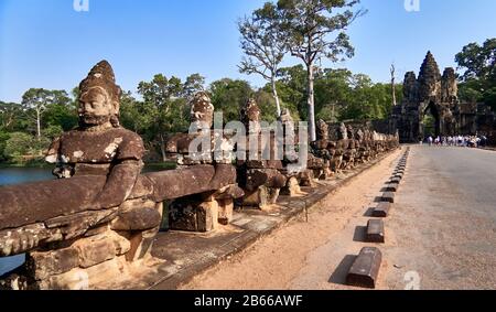 Archeological site ,The South Gate of Angkor Thom leads to Bayon Temple. Lined with 54 stone figures engaged in a performance of a famous Hindu story, it extends about 50 metres across a moat. Stock Photo