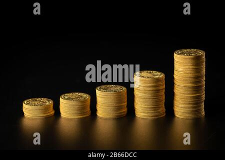 Closeup of stacks of old gold coins in a row, black background Stock Photo