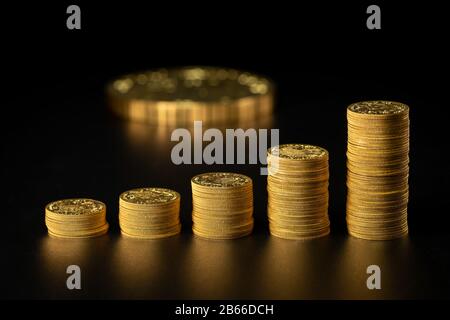 Closeup of stacks of old gold coins in a row, big coin in the background Stock Photo