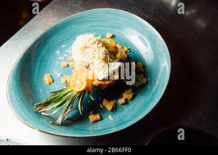 Freshly prepared salad lies inside the pineapple, which is cut lengthwise, sprinkled with grated cheese. Everything looks very appetizing. Stock Photo