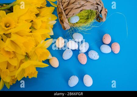 Happy Easter. Easter holiday decorations on trendy colored classic blue background. Creative spring composition with Easter elements - flowers and eggs in basket. Celebrating Easter concept at spring. Stock Photo