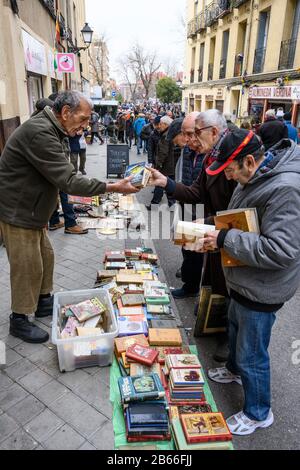 Bargain hunters browsing books in the Rastro flea market around the Plaza de Cascorro between La Latina and Embajadores,  Madrid, Spain. Stock Photo