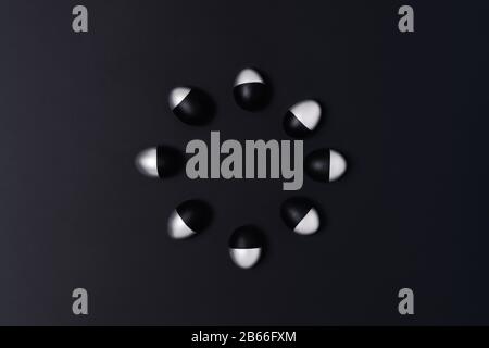 Circle made of black and silver Easter eggs on dark grey background. Flat lay, top view, copy space. Stock Photo