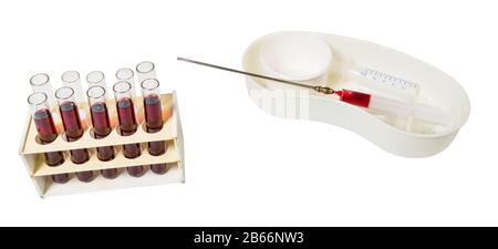 Medical laboratory equipment. Group of glass test tubes with red liquid in rack. Syringes and long metal needle in plastic dish. Clinical examination. Stock Photo