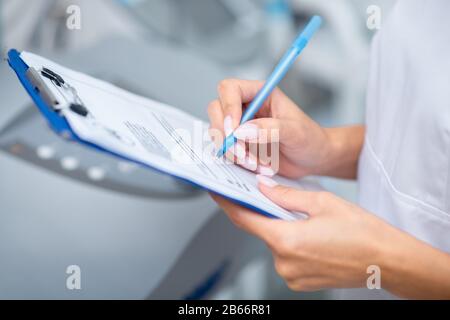 Close up of woman holding pen while making notes after seeing client Stock Photo