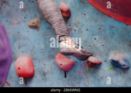 Foot of female climber on artificial boulder. Close-up view of professional shoe Stock Photo