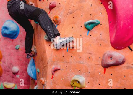 Foot with shoes of female climber on artificial boulder wall at gym Stock Photo