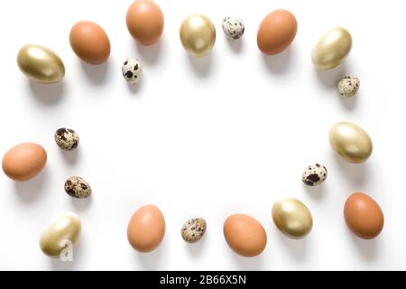 Easter frame of golden, quail, chicken eggs on white background. View from above. Space for text. Stock Photo
