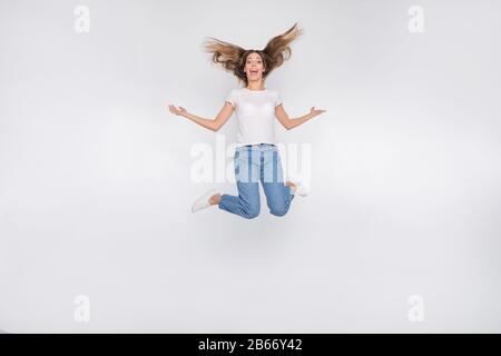 Full length body size photo of crazy funny cute nice attractive girl jumping high wearing jeans denim happy while isolated with white background Stock Photo