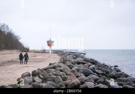 10 March 2020, Schleswig-Holstein, Lübeck-Travemünde: Two walkers are on the almost deserted beach at the water of the Baltic Sea. Photo: Daniel Bockwoldt/dpa Stock Photo