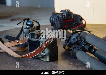 three dslr cameras and a tripod lying on a table Stock Photo