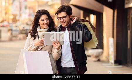 Lovely couple using tablet and walking down the streets Stock Photo