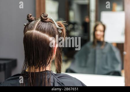 Dividing hair of woman in sections with clips during hair extension in beauty salon. Stock Photo