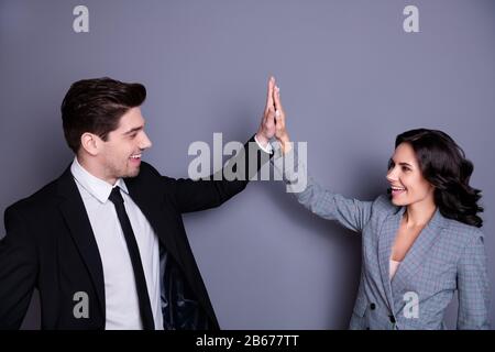 Profile side photo of cheerful wavy curly brunette haired couple giving high five wearing black jacket blazer isolated over grey background Stock Photo