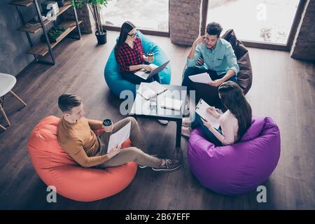 Top above high angle view of smart clever interns specialists executive junior managers reviewing financial documentation sitting on bag chair at Stock Photo