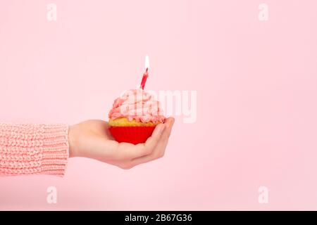 Tasty cupcake with birning candle on a pink background. Monochrome birthday concept with cupcake and pink frosting. Copy space. Stock Photo