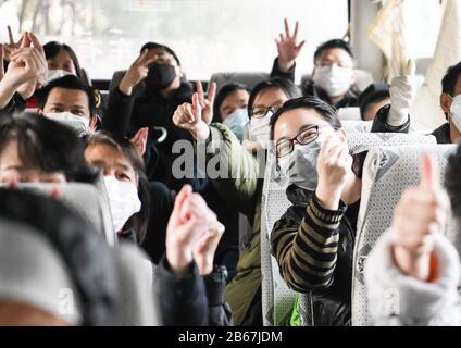 Wuhan, China. 10th Mar 2020. Cured coronavirus patients gesture on the bus home after a 14-day quarantine for medical observation at a rehabilitation center in Wuhan, central China's Hubei Province, March 10, 2020. A total of 143 cured coronavirus patients who were discharged from hospital finished their 14-day quarantine for medical observation on Tuesday at the rehabilitation center based in Wuhan Vocational College of Software and Engineering. Credit: Xinhua/Alamy Live News Stock Photo