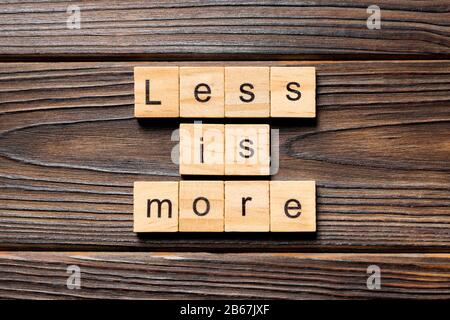 less is more word written on wood block. less is more text on table, concept. Stock Photo