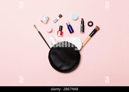 Top view od cosmetics bag with spilled out make up products on pink background. Beauty concept with empty space for your design. Stock Photo