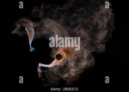 Bursting balloon full of coloured powder and glitter on a black background Stock Photo