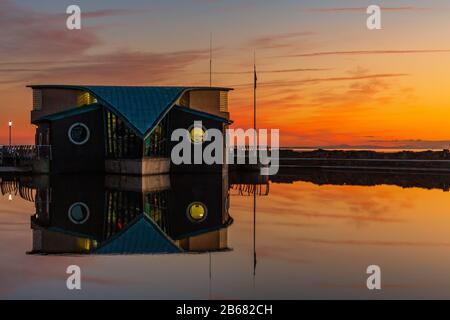 st annes lifeboat station is reflected in the boating lake in front of a beautiful golden sunset. home to all weather lifeboat Barbara anne Stock Photo