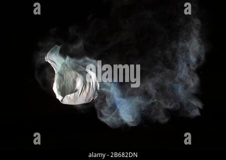 Bursting balloon full of coloured powder and glitter on a black background Stock Photo