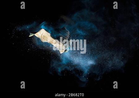 Bursting balloon full of coloured powder and glitter on a black background Stock Photo