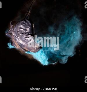 Bursting balloon full of coloured powder and glitter on a black background Stock Photo
