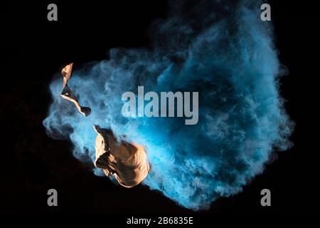 Bursting balloon full of coloured powder and glitter on a black background Stock Photo