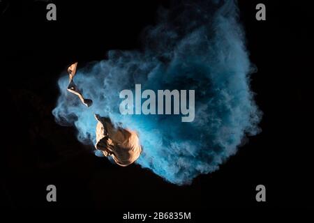 Bursting balloon full of coloured powder and glitter on a black background Stock Photo