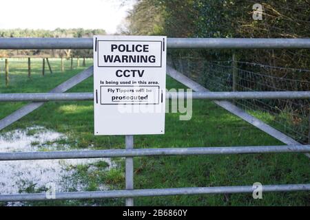 Police sign on a farm gate warning of the use of CCTV to combat fly tipping Stock Photo