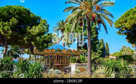 Nice, France - October 4, 2018: View to a park with a historic carousel under palm trees in Nice. Stock Photo