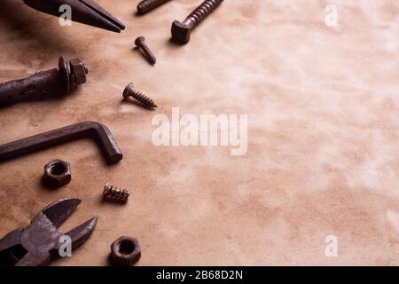 Variation of old rusty handy tools on grunge background with copy space. Pliers, bolts and nuts, screw and other industrial equipment. Stock Photo