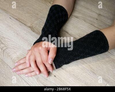 Black fashionable wool knitted wrist warmers on the woman hands Stock Photo